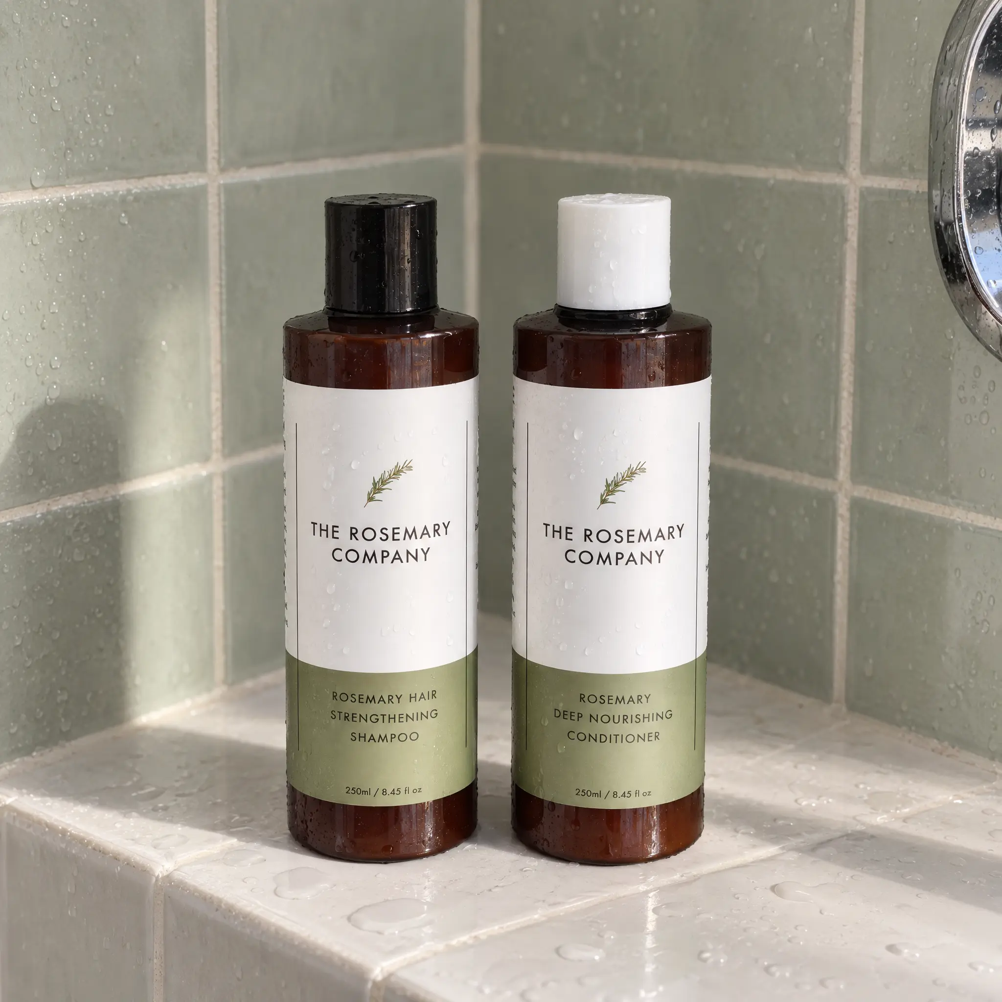 The Rosemary Company Shampoo and Conditioner bottles on a tiled shower ledge.